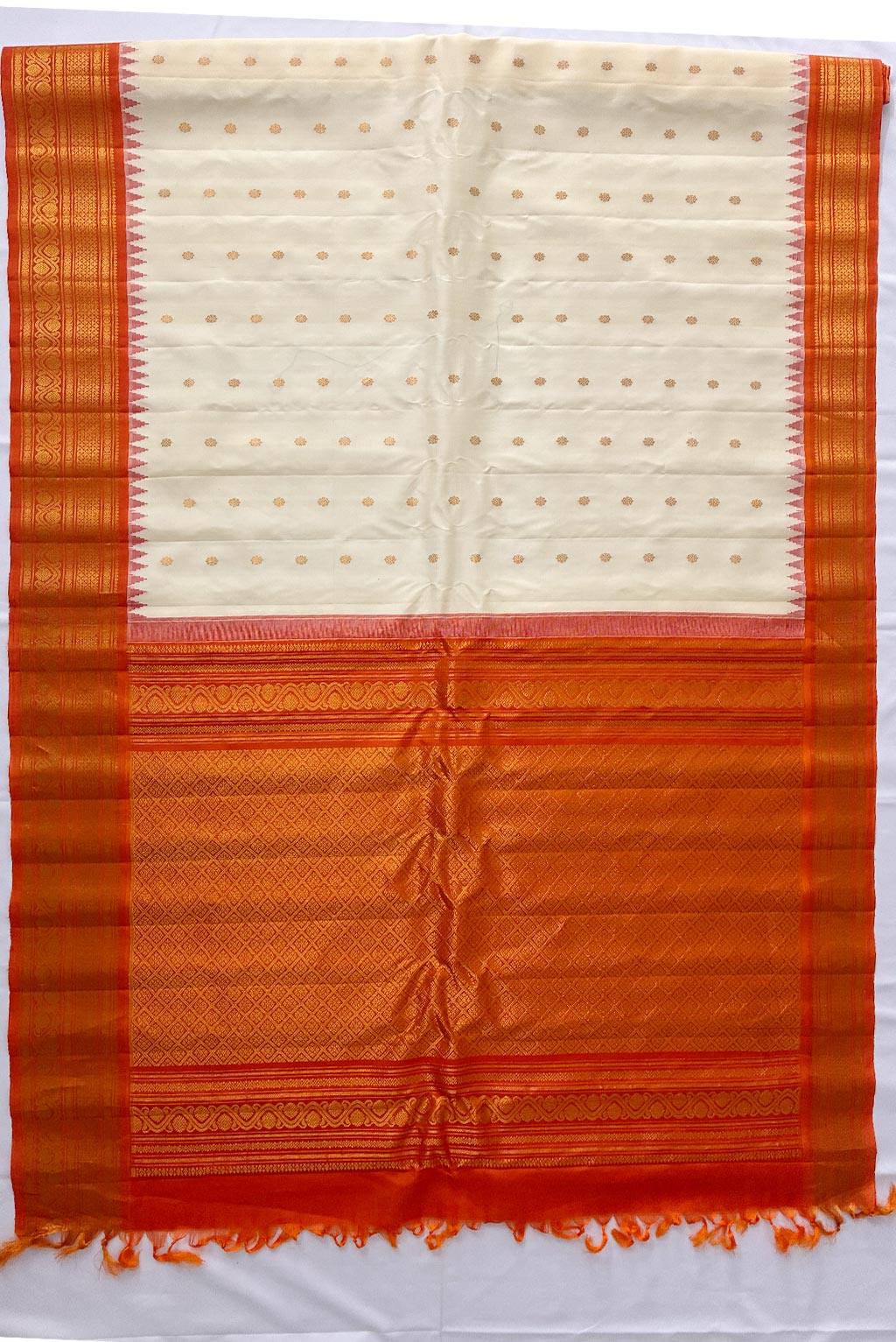 gadwal Cream half white shade butas, orange border handloom silk saree